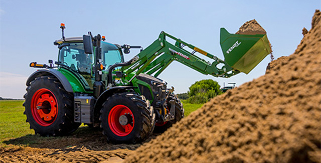 Fendt 600 Vario tractor loading soil with front loader on a sunny day